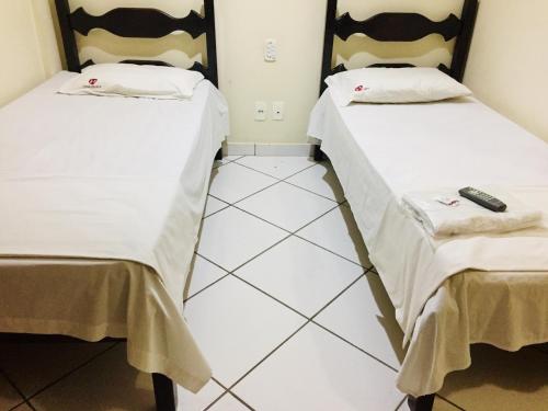 伊帕廷加Hotel Oliveira - By UP Hotel的两张睡床彼此相邻,位于一个房间里