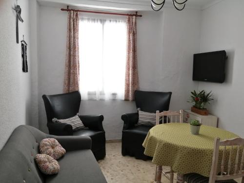 普里埃格·德·科尔多巴Casa de La Costurera的客厅配有两把椅子、一张沙发和一张桌子