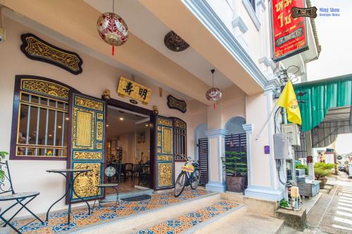 普吉镇明寿精品屋酒店的一座带门的建筑,外面有桌子和摩托车