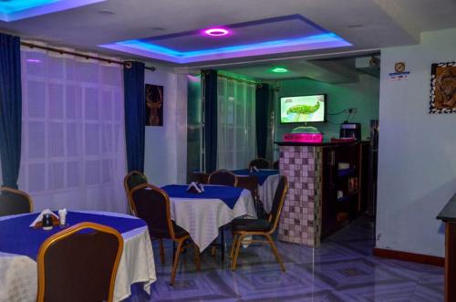 纳库鲁Kentania Hotel & Spa, Nakuru - Kenya的一间带桌椅和电视的用餐室