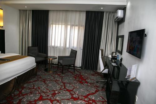 拉各斯GreenPoint Hotel的酒店客房带一张床、一张桌子和椅子