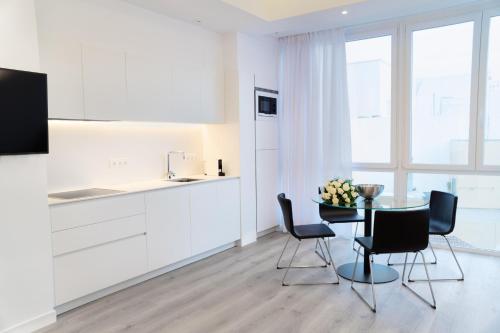 洛斯·亚诺斯·德·阿里丹Lauser City Suites的白色的厨房配有桌椅和柜台。