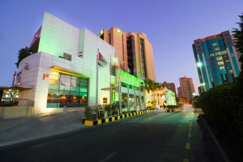 科威特Holiday Inn - Suites Kuwait Salmiya, an IHG Hotel的夜街,有建筑物和街道