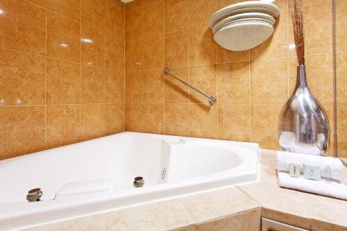 蒙特雷蒙特雷加莱里亚斯圣赫罗尼莫智选假日酒店的一间带白色浴缸和大花瓶的浴室