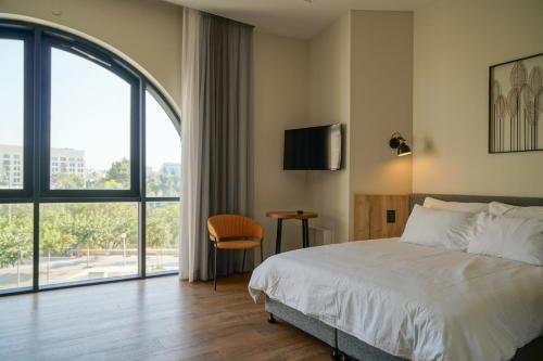 耶路撒冷Apartique Hotel的酒店客房设有一张床和一个大窗户