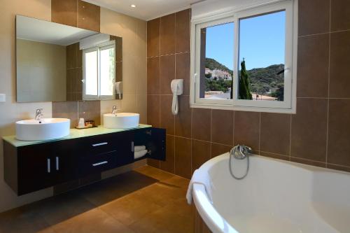 博尼法乔阿马多内塔酒店的一间带两个盥洗盆、浴缸和窗户的浴室