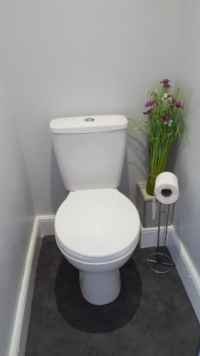 KentMango Lodge的浴室内白色的厕所,鲜花盛开