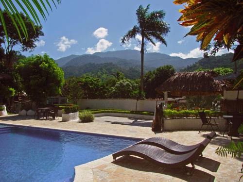 埃尔扎伊诺Villa Cata Hotel的坐在游泳池边的长凳,游泳池后面有山地背景
