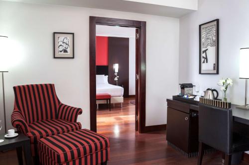 布宜诺斯艾利斯NH布宜诺斯艾利斯城市酒店的一间带椅子和书桌的房间以及一间卧室