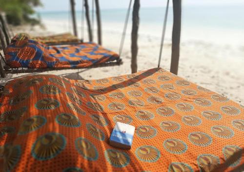 帕杰Jaribu Beach Hotel的沙滩边的沙滩上一排毯子