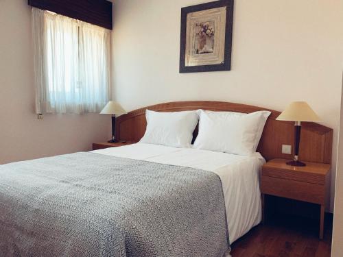 蒙塔莱格里Casa Machado的一间卧室配有一张带白色床单和两盏灯的床。