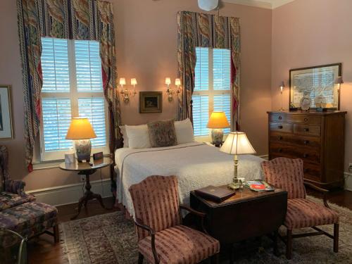 梅肯1842 Inn的一间卧室配有一张床、两把椅子和一张桌子