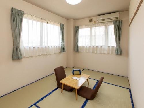 石卷市Tabist Business Ryokan Duck Ishinomaki Hebita的客房设有桌椅和窗户。