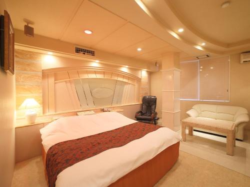 堺市Hotel Fine Garden Senboku的一间卧室配有一张大床和一把椅子