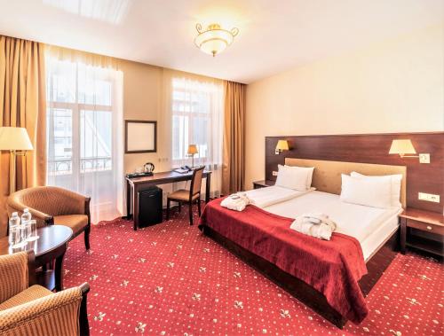 里加瑞克斯韦尔老里加宫酒店的配有一张床和一张书桌的酒店客房