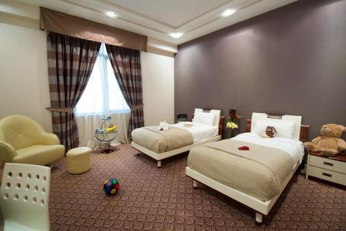 麦纳麦One Pavilion Luxury Serviced Apartments的一间卧室配有两张床、一把椅子和泰迪熊