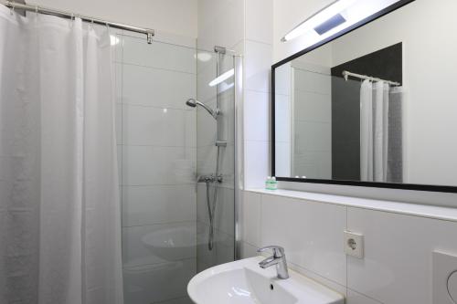 科隆Art Rock Downtown Hotel的一间带水槽、淋浴和镜子的浴室