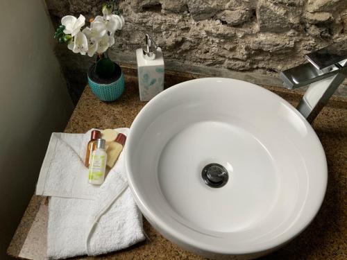 普拉亚Techas City Center Luxurious Studio的浴室内设有一个白色水槽,配有毛巾和鲜花