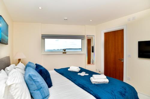 斯旺西Just Stay Wales - Meridian Quay Penthouses的一间卧室配有蓝色的床和毛巾
