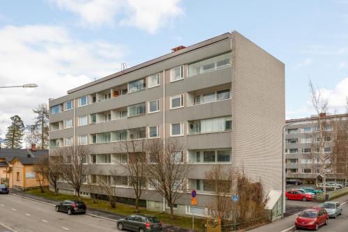 库奥皮奥Kotimaailma Kuopio的停车场内有车辆停放的公寓大楼