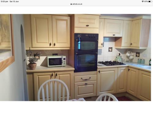 莱德伯里1 The Mews Cottages的厨房配有白色橱柜和炉灶烤箱。