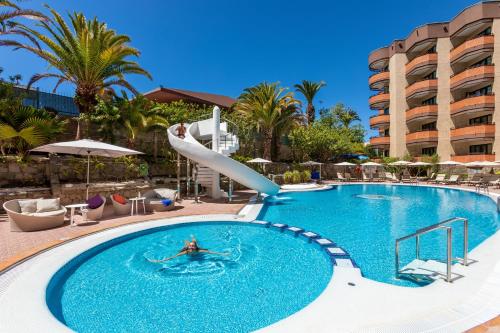 英格兰海滩大加那利岛穆尔海王星酒店 - 仅限成人入住的在酒店游泳池滑梯上的人