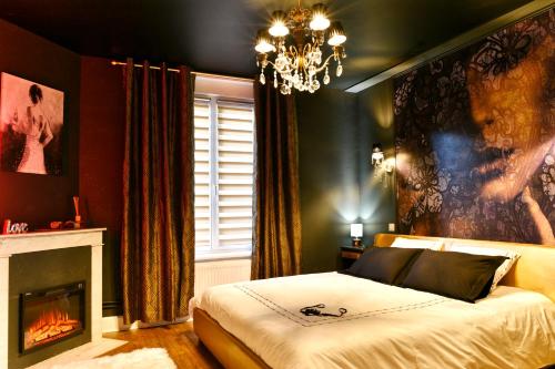 南希MoonLOVE, SPA/Sauna et Jacuzzi privés, charme et détente.的一间卧室配有一张带壁炉和吊灯的床。