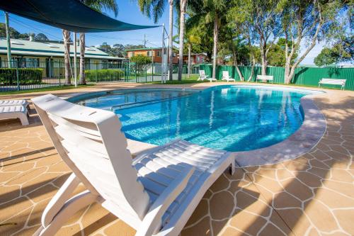 巴特曼斯贝巴特曼斯贝滨江假日公园酒店的游泳池旁设有两把白色椅子