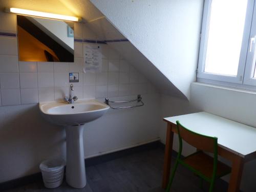 蓬蒂维Auberge de Jeunesse HI Pontivy的一间带水槽和桌椅的浴室