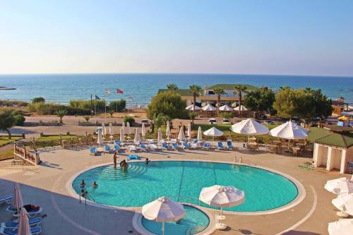 法马古斯塔Kaplica Hotel的一个带遮阳伞和海洋的大型游泳池