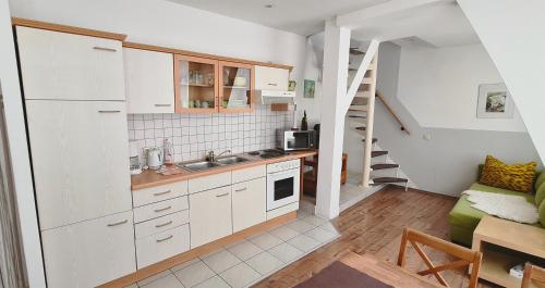 施特拉尔松德Altstadtfreude Stralsund的一间小厨房,配有白色的橱柜和楼梯