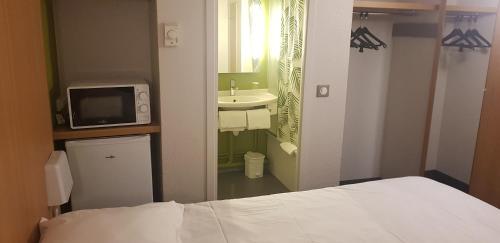 沙斯讷伊迪普瓦图Kyriad Direct Poitiers - Gare du Futuroscope的一间卧室配有一张床,浴室设有水槽