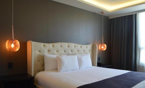 帕丘卡德索托Casa Basalto的卧室配有白色的床,上面有两盏灯