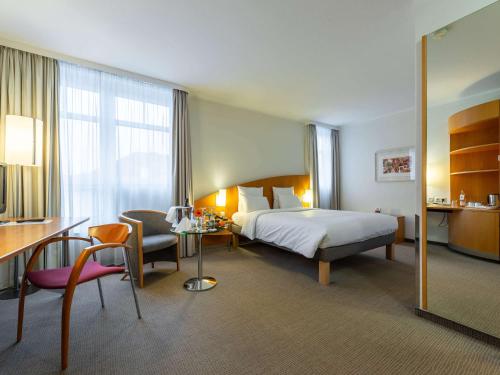 美因茨诺富特美英茨酒店的酒店客房带一张床铺、一张书桌和一间卧室