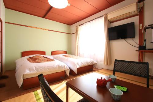 对马市Banshoukaku的酒店客房设有两张床、一张桌子和电视。