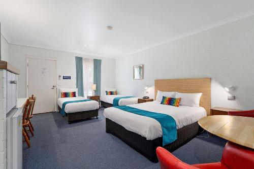 沃东加Econo Lodge Border Gateway Wodonga的酒店客房带两张床和一张桌子以及椅子。