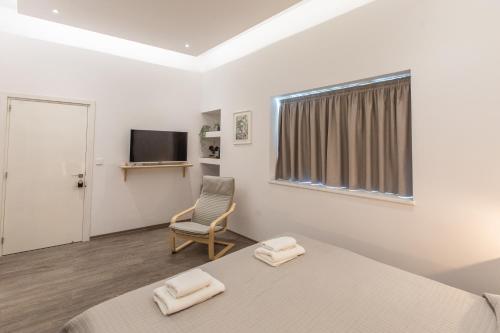 帕福斯Rooms - Unique staying in Paphos Centre的一间卧室配有一张床、一把椅子和电视