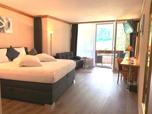 洛伊克巴德Hotel Quellenhof Leukerbad的酒店客房设有床和客厅。