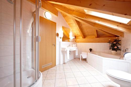 加尔米施-帕滕基兴Hotel Schatten的带淋浴、盥洗盆和浴缸的浴室