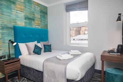 伦敦Paddington Park Hotel的一间卧室配有一张蓝色床头板的床