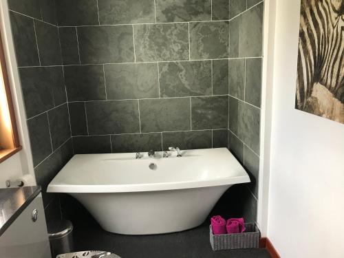 凯里肯Strathspey的浴室设有白色浴缸,浴室设有瓷砖墙
