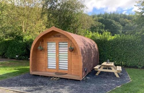 多尔盖罗Glamping Huts in Heart of Snowdonia的院子里的木棚和野餐桌
