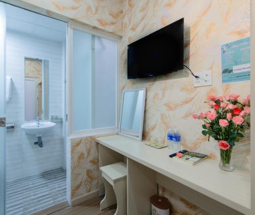 大叻Nắng Chiều Central Hotel的一间带水槽的浴室和墙上的电视
