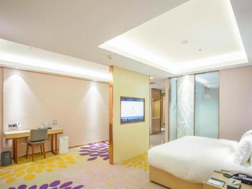 锦州Lavande Hotel Jinzhou Jiefang Road Kaixuan Building的酒店客房配有一张床、一张书桌和一台电视。