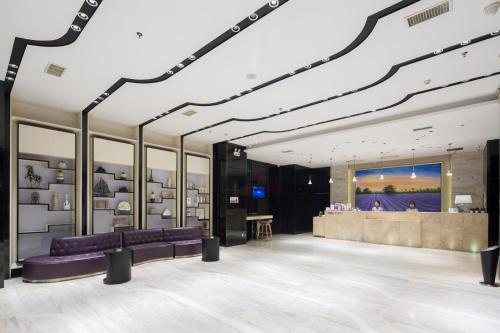 长沙Lavande Hotel Changsha High-speed Railway Station Shuling的一个带紫色沙发的商店大堂和一间酒吧