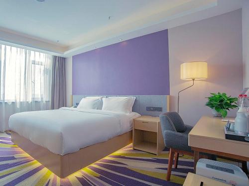 邯郸Lavande Hotel Handan Congtai Park New Century Plaza的一间卧室配有一张床、一张桌子和一把椅子
