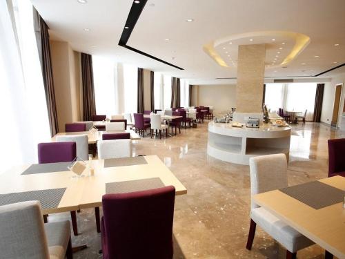 九江Lavande Hotel Jiujiang Jiujiang College的一间在房间内配有桌椅的餐厅