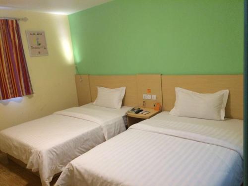 Zhijin7Days Inn Bijie Zhijin Chengguan的绿墙客房内的两张床