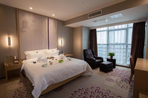 徐州Lavande Hotel Xuzhou West Exit of High Speed Rail Station Branch的酒店客房带一张大床和一把椅子