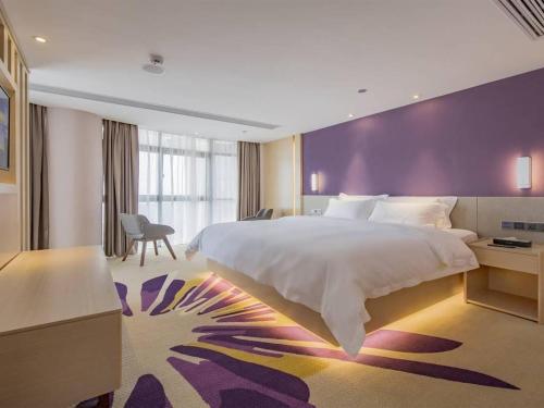 南昌Lavande Hotel Nanchang Shuanggang Metro Station Caida University的一间卧室设有一张大床和紫色的墙壁